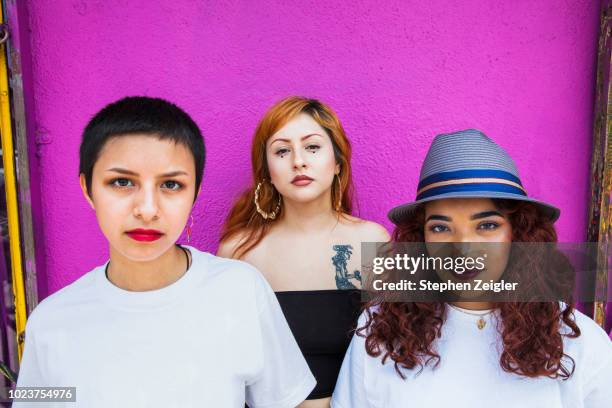 Three young women in front of pink background