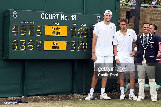 John Isner of USA poses after winning on the third day of his first round match against Nicolas Mahut of France with Chair Umpire Mohamed Lahyani on...