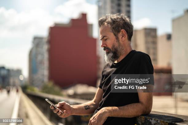 mature man using mobile portrait at minhocao, sao paulo, brazil - person on mobile phone imagens e fotografias de stock