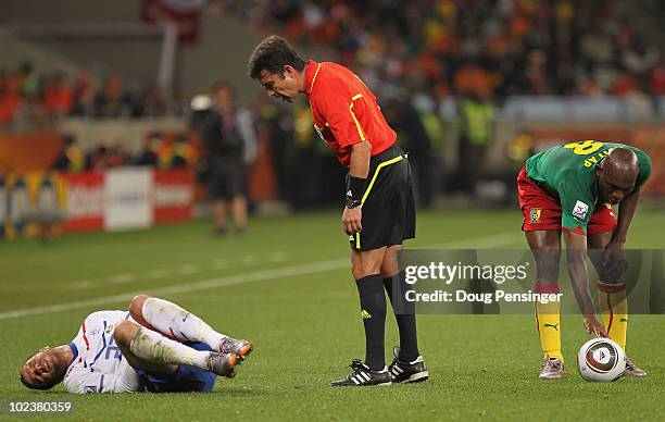 Rafael Van der Vaart of the Netherlands lies on the pitch injured as referee Pablo Pozo stands over him while Geremi of Cameroon places the ball...