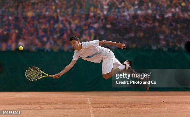 tennis player diving to hit ball on clay court - tennis stock-fotos und bilder