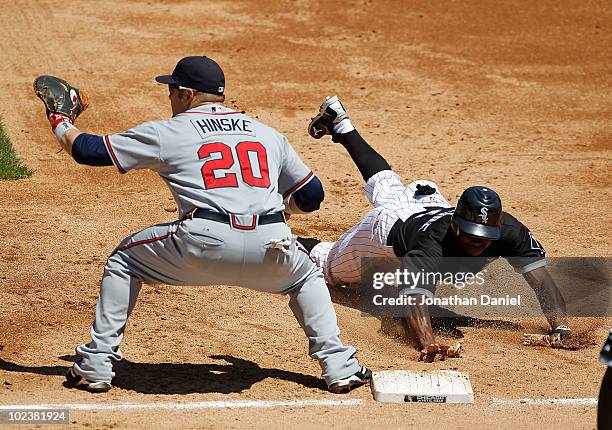 Juan Pierre of the Chicago White Sox dives back to first base as Eric Hinske of the Atlanta Braves awaits the throw at U.S. Cellular Field on June...