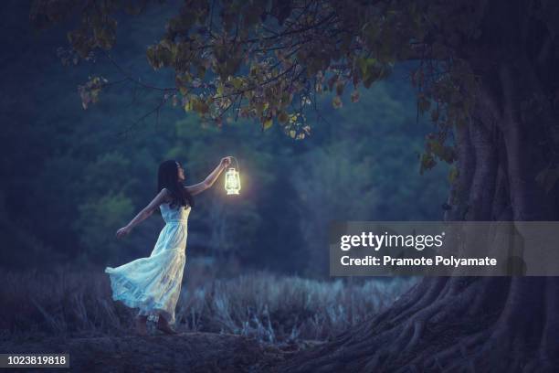 beautiful girl in white holding a lantern in the autumn forest shining under the trees. - menina fantasia bonita imagens e fotografias de stock