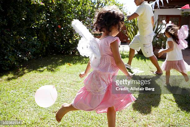 girls dressed as fairies, running in garden - feenkostüm stock-fotos und bilder