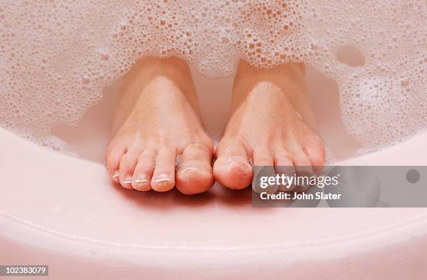 woman's feet resting against bath tub with bubbles - pied humain photos et images de collection