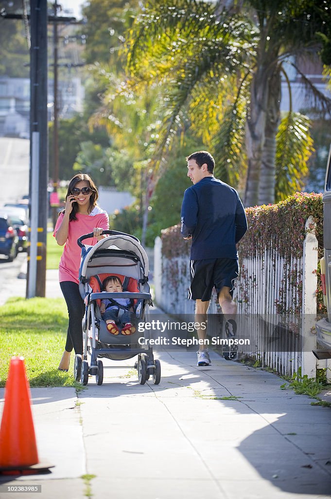 Stylish young Mom with baby, runner passing