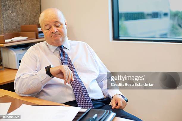 businessman checks his watch - bored worker fotografías e imágenes de stock