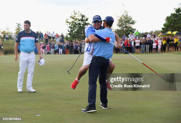 Andrea Pavan of Italy victory with his caddie on the 18th green as Padraig Harrington of Ireland look son during day four and final round of the the...