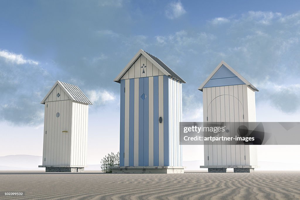 Three beach huts on an empty beach