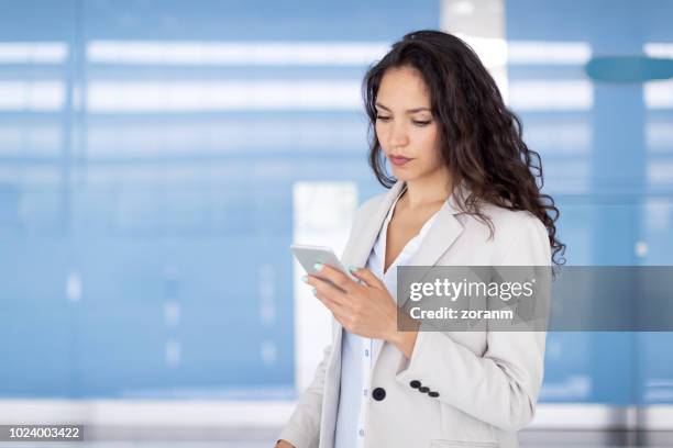 mujer de negocios mediante teléfono inteligente - arab businesswoman with books fotografías e imágenes de stock