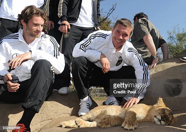 Lukas Podolski and Arne Friedrich of the German National Team stroke a lion cup during a visit at the Lion Park on June 25, 2010 in Lanseria, South...