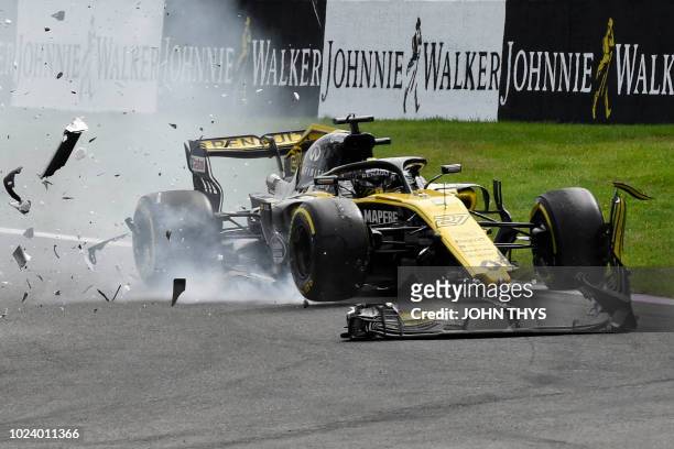The car of Renault's German driver Nico Hulkenberg is damaged as McLaren's Spanish driver Fernando Alonso crashes during the first lap of the Belgian...