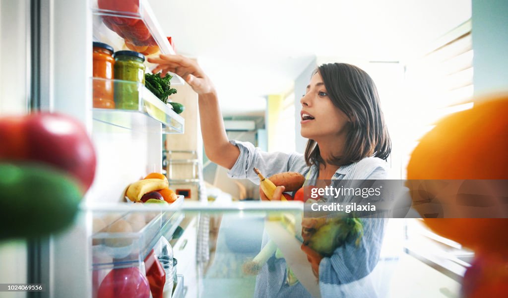 Mujer recogiendo algunas frutas y verduras de la nevera