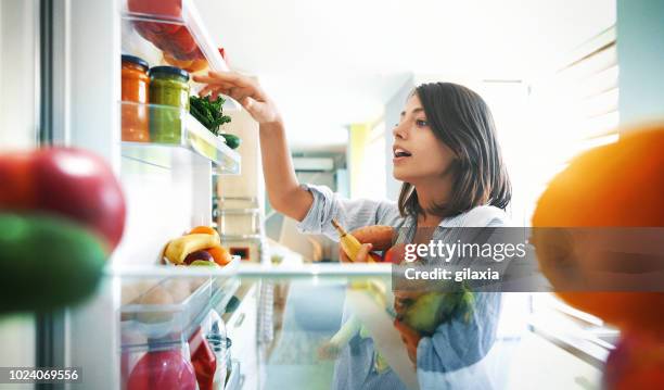 mujer recogiendo algunas frutas y verduras de la nevera - frescura fotografías e imágenes de stock