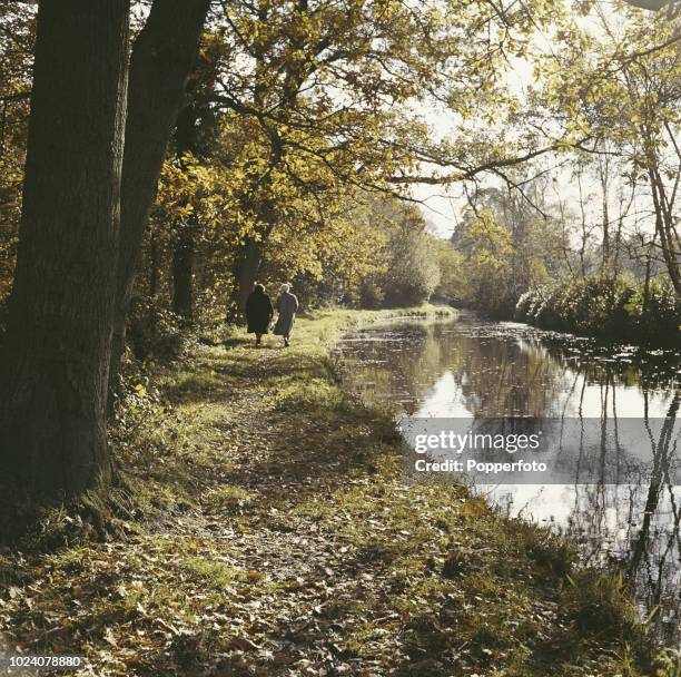 View of two women walking along a towpath beside the Basingstoke Canal in Hampshire, England in 1961.