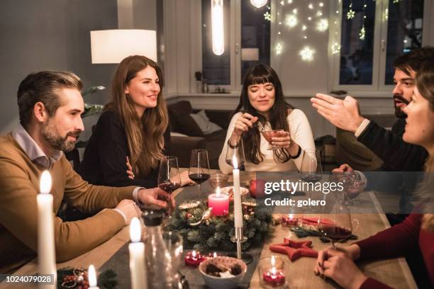 young happy people talking at christmas table - christmas party host stock pictures, royalty-free photos & images