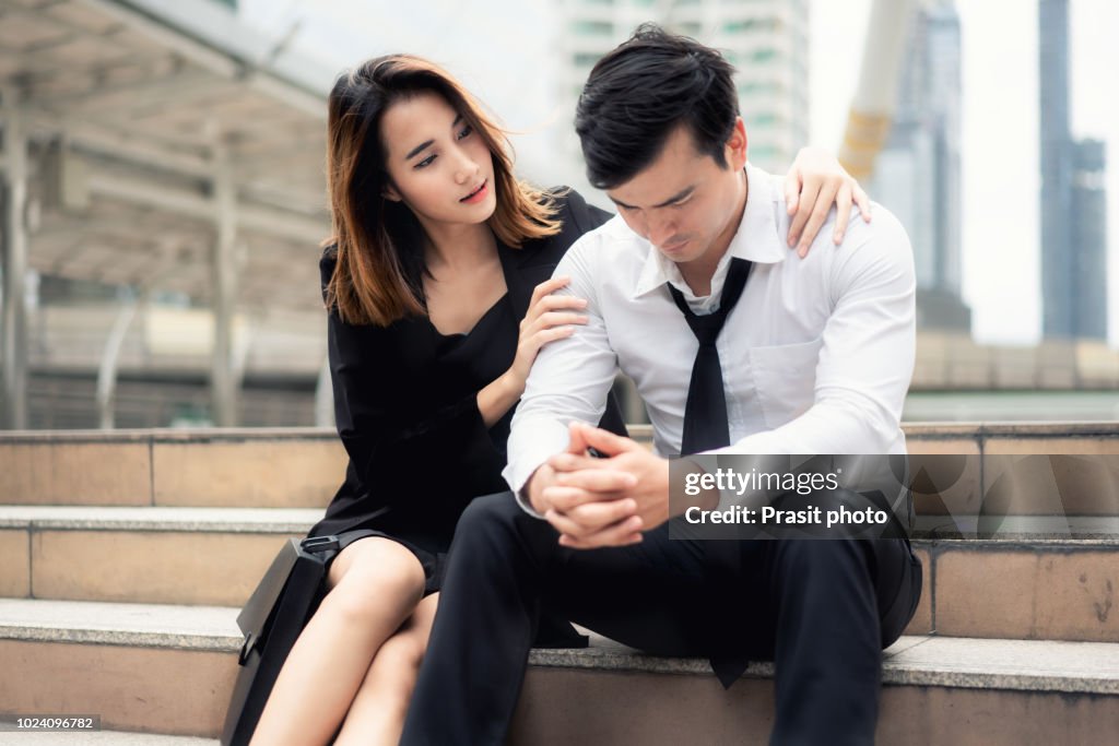 Confident businesswoman tapping male colleague on shoulder supporting him. Business relationship concept