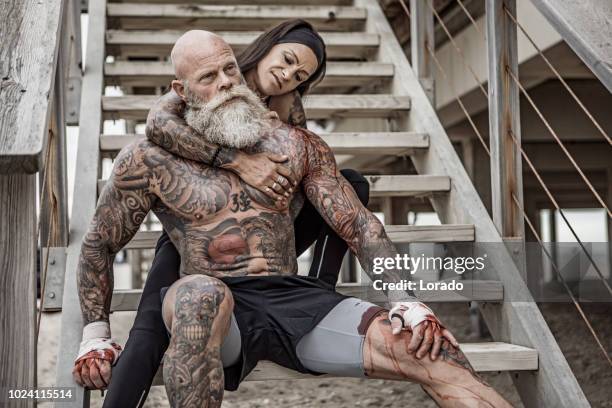 tattooed senior couple posing during workout - muscle men at beach stock pictures, royalty-free photos & images