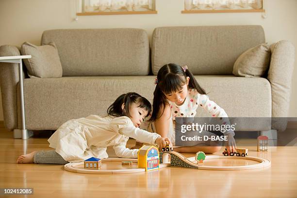 girls playing with toy trains at living room. - home base stockfoto's en -beelden