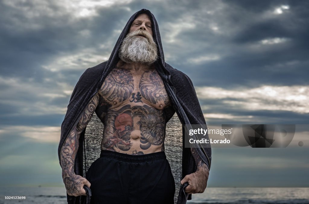 Homme Senior tatoué posant au cours de la séance d’entraînement