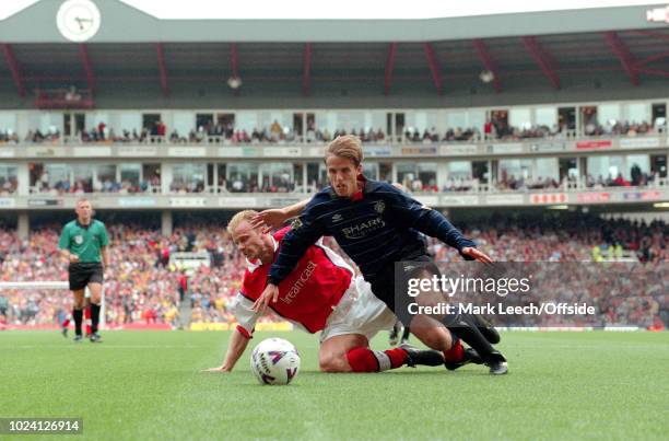 August 1999 - Premiership Football - Arsenal v Manchester United - Dennis Bergkamp of Arsenal goes down under a challenge from Phil Neville of...