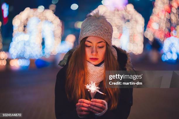 teenage girl holding burning sparkler during christmas - homeless winter stock pictures, royalty-free photos & images