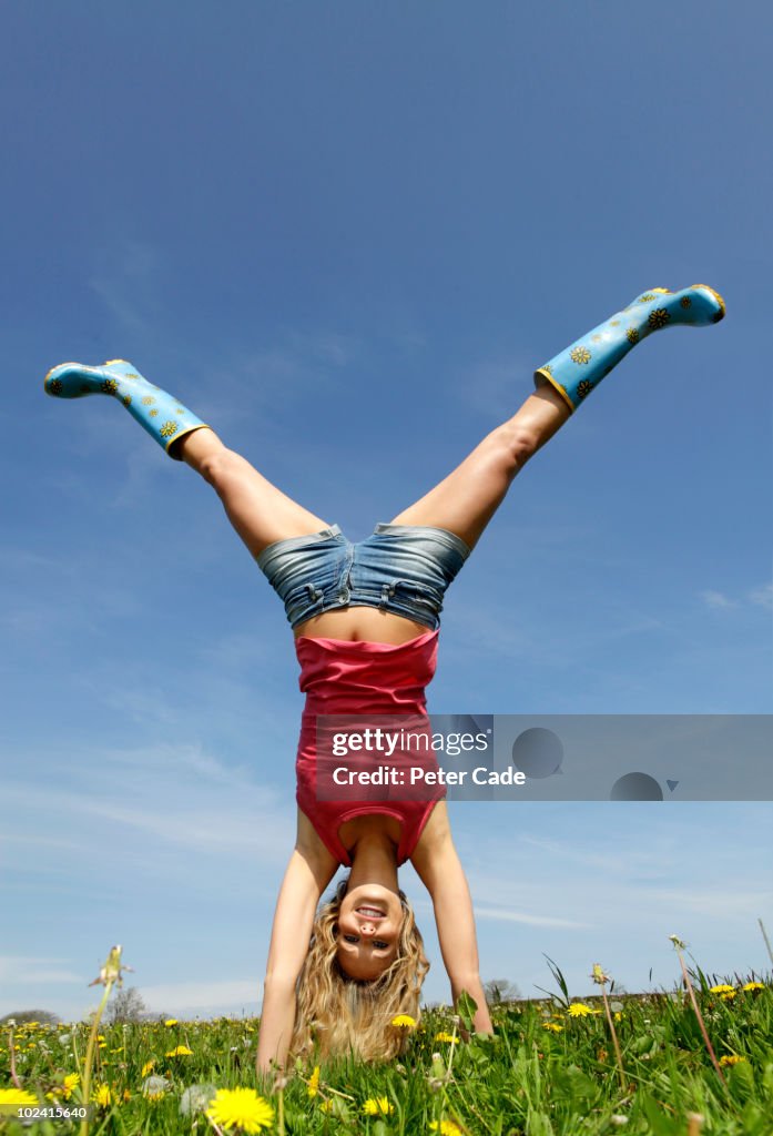 Woman doing handstand in field