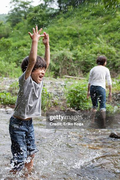 boy splashing water in river - asian water splash stock-fotos und bilder