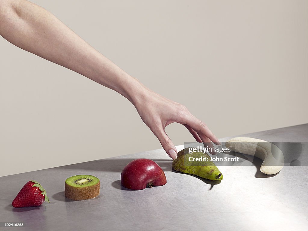 Woman picking up piece of fruit
