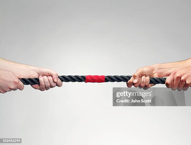 hands pulling on rope during game of tug-of-war - confrontación fotografías e imágenes de stock