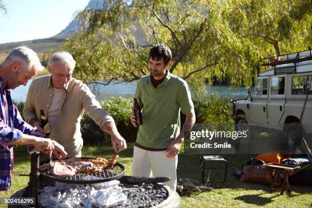 three men barbecuing at camp site - car grill stock pictures, royalty-free photos & images