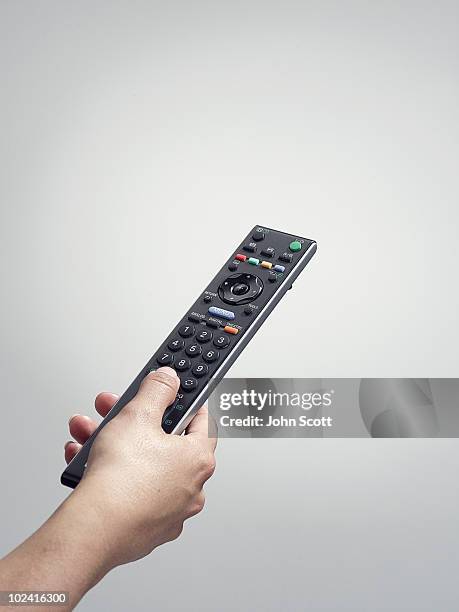 hand holding a tv remote control - remote stock pictures, royalty-free photos & images