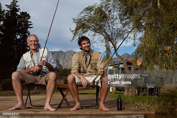 father and son fishing on jetty - friends smile bildbanksfoton och bilder