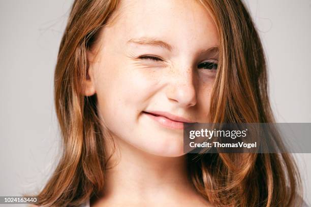 natuurlijke portret van een schattig meisje winking - gezicht haar schoonheid fun ogen sproeten smile - winking stockfoto's en -beelden