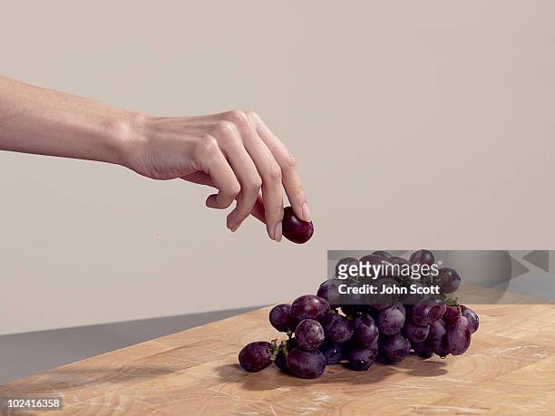 woman taking a grape - grappe de raisin photos et images de collection