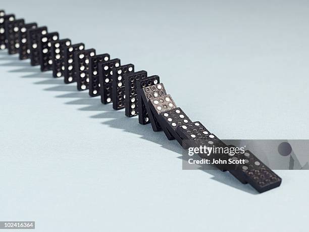 row of dominoes toppling over - dominos falling stock pictures, royalty-free photos & images