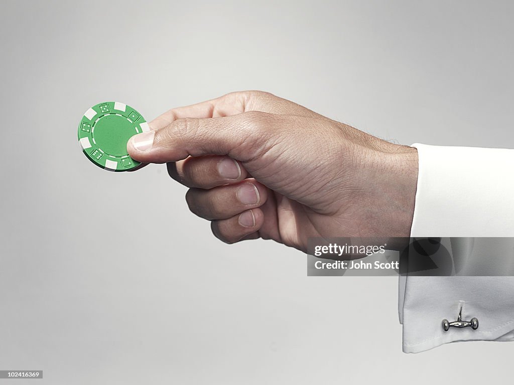 Hand holding a poker chip