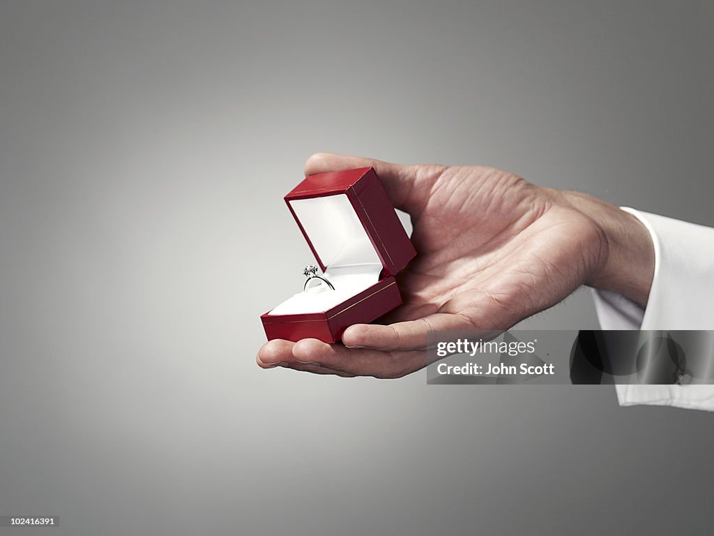 Man holding engagement ring, close-up of hand