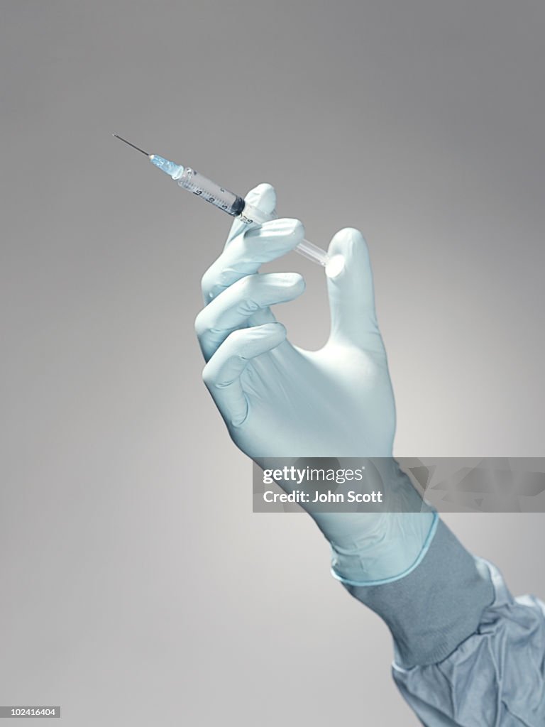 Hand holding a syringe 