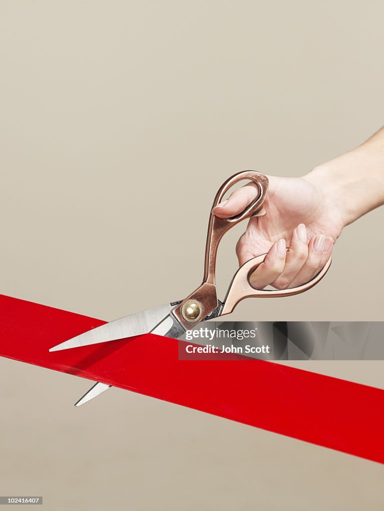 Woman using scissors to cut opening ribbon