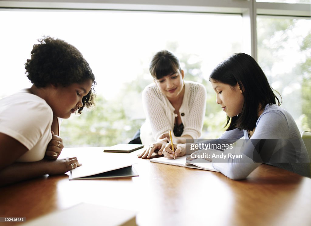 Teacher helping children study in library