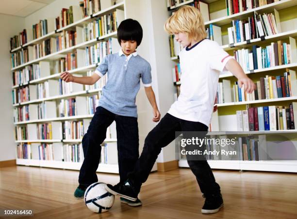 two boys playing soccer in library - fußball 2 jungs stock-fotos und bilder