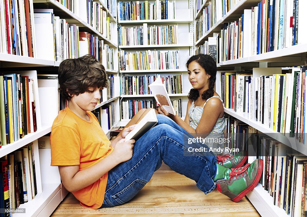 Two children reading on floor in library stacks