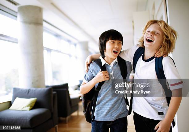 two boys laughing with arms around each other  - enfant cartable photos et images de collection