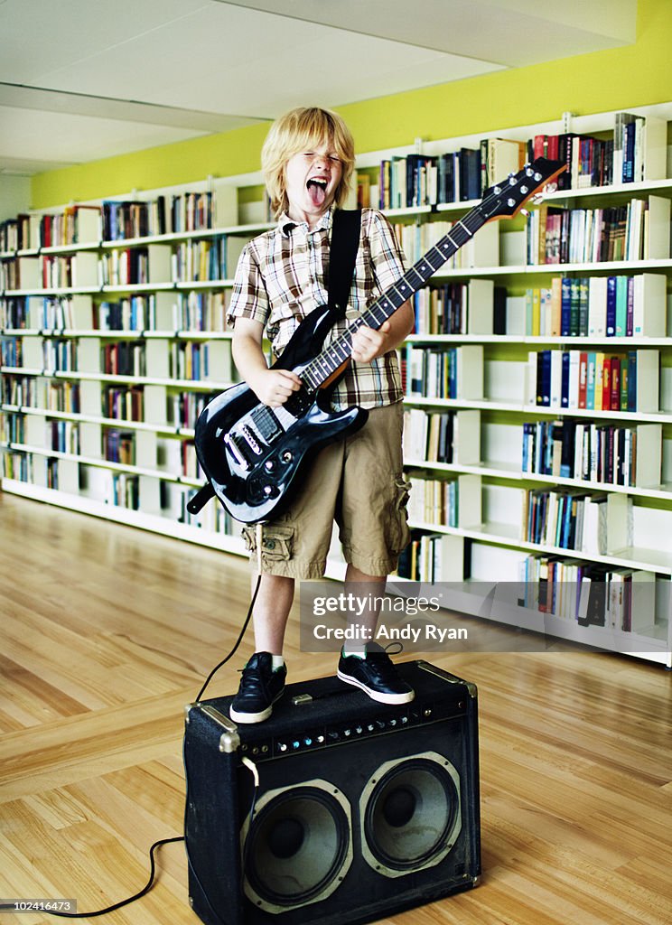 Boy playing electric guitar in library