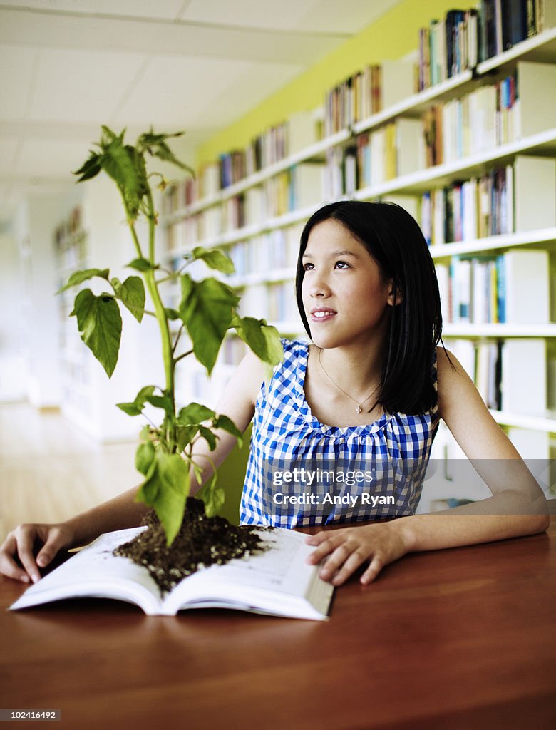 Girl looking at plant growing from book