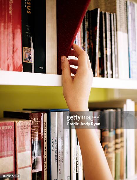girls hand choosing book from library shelf - choosing a book stock pictures, royalty-free photos & images
