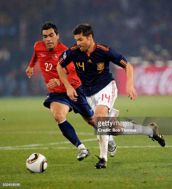 Xabi Alonso of Spain dribbles past Esteban Paredes of Chile during the 2010 FIFA World Cup South Africa Group H match between Chile and Spain at...
