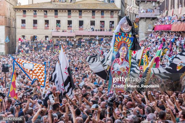 menschen mit fahnen am "piazza di campo" während des "palio di siena" auf stadt siena, italien. - palio di siena stock-fotos und bilder