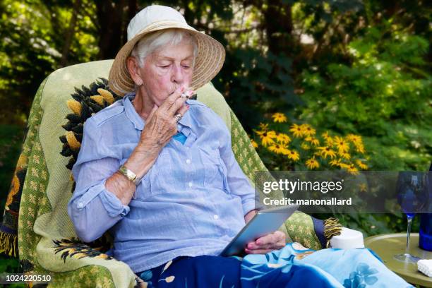 happy senior woman smoking marijuana joint as cannabis medicinal - mature woman herbs stock pictures, royalty-free photos & images